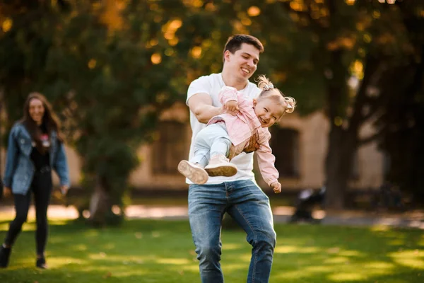 Lycklig far leker med dottern snurrar med ett barn i famnen — Stockfoto