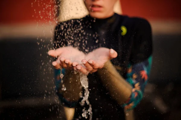 Flicka i svart dykning kostym står under duschen placera händerna under vatten — Stockfoto