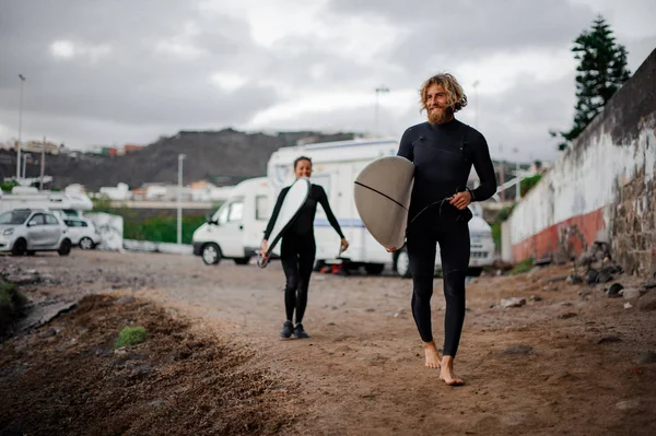 Deux surfeurs souriants avec les planches de surf marchant jusqu'au bord de la mer — Photo