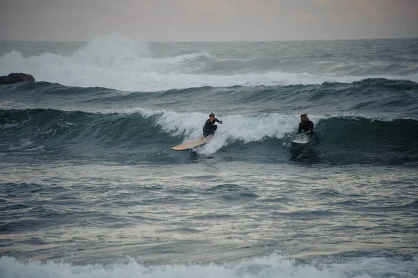 Two man and woman surfers caught a small wave on surf boards — Stock Photo, Image