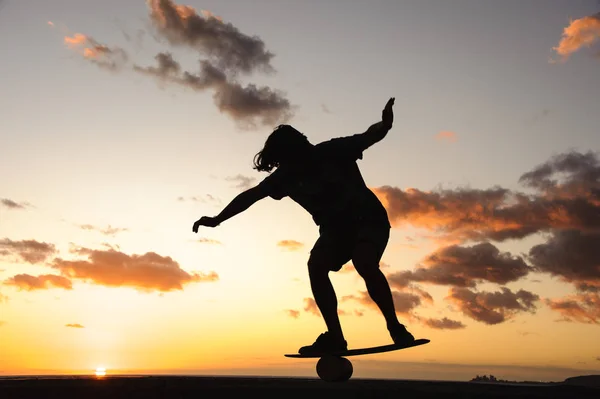 Silhouet van de man die balanceert op het balansbord aan de kust van de oceaan — Stockfoto