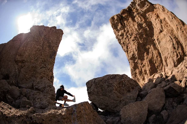 Człowiek stojący na tablicy balansowej na jednej nodze pośród skał w górach — Zdjęcie stockowe