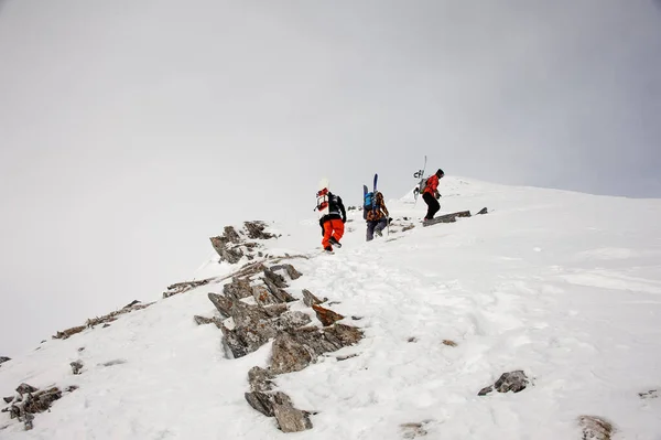 Three sportsmen with equipment hiking up the mountain — Stockfoto