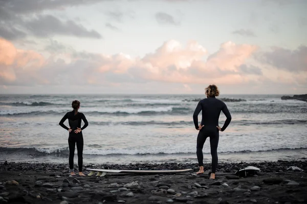 Mężczyzna i kobieta z deskami surfingowymi stojącymi na brzegu morza — Zdjęcie stockowe