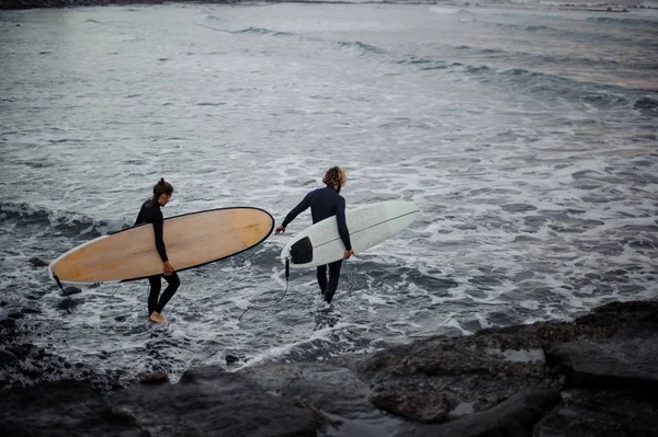 Homme et femme avec planches de surf allant à l'eau — Photo