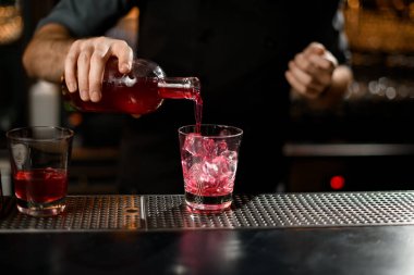 Barmen şişeden cama içki dolduruyor.