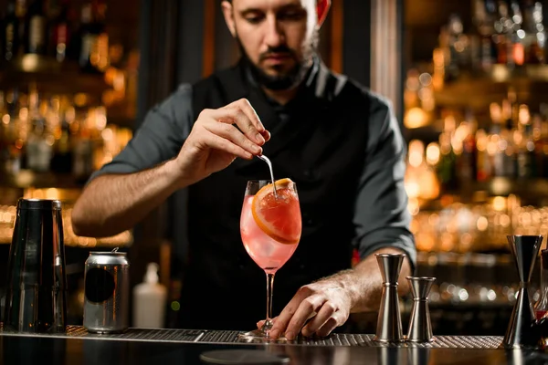 Barman doet grapefruitschijfje in een drankje — Stockfoto