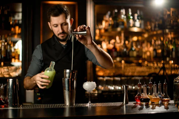 Bartender pouring cocktail with liquor using jigger and shaker — ストック写真