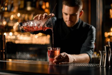 Barmen alkolü süzgeçten cama döker.