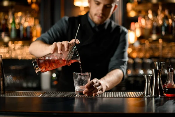 Lähikuva baarimikko kaatamalla cocktail siivilä — kuvapankkivalokuva