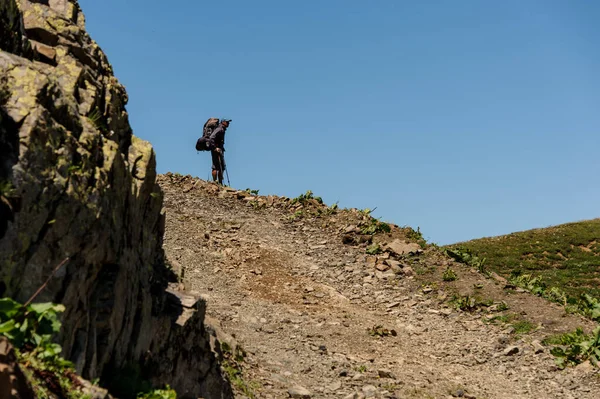 Traveller stands on a cliff near mountains — ストック写真