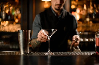 Barmen martini için bir kokteyl bardağı alıyor.