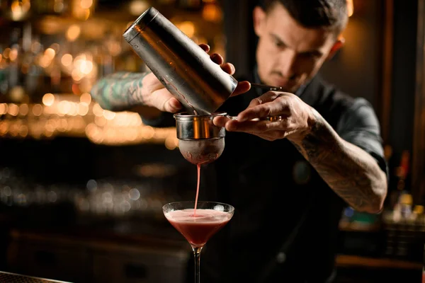 Barista versando cocktail dallo shaker al setaccio — Foto Stock