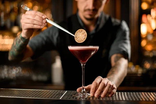 Barmen kokteylin içine bir dilim limon koydu.