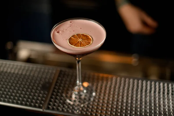 Red cocktail with pink scum decorated with dried orange slice — Stockfoto