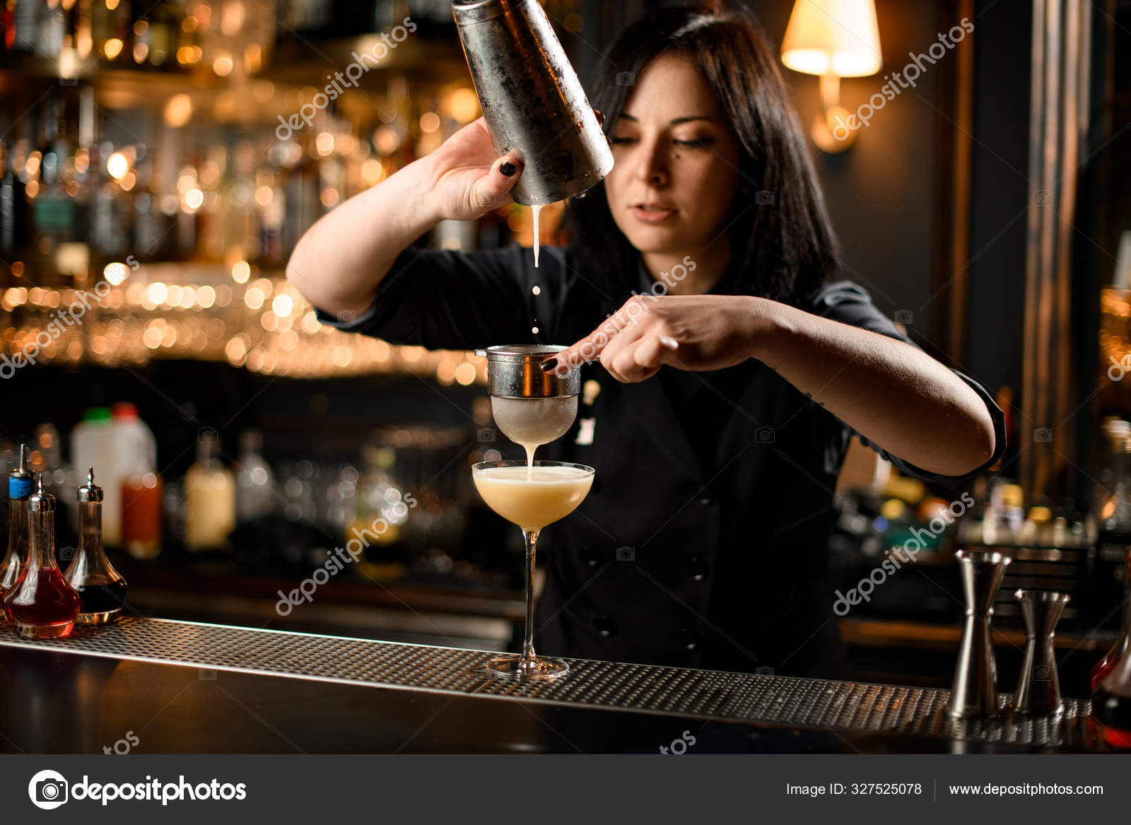 Bartender girl stirring a delicious cocktail with a steel spoon in