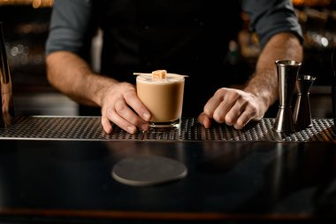Barmen, şişte şekerle süslenmiş kremalı alkolik içeceği servis ediyor.