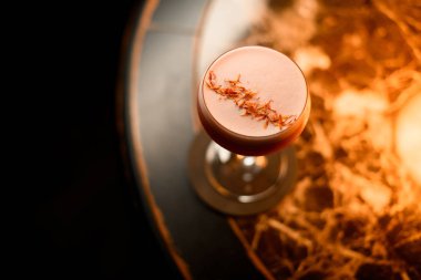 Barda sarı çiçek yapraklarıyla süslenmiş pembe alkollü kokteyl içeceği.