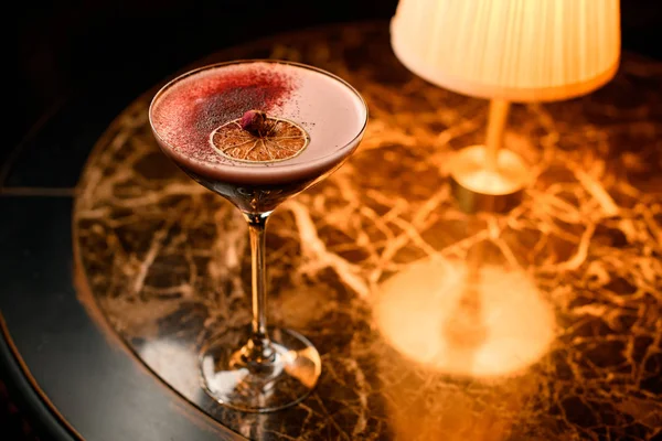 Delicious red cocktail decorated with dried orange slice, red spices and little dried rose bud — Stockfoto
