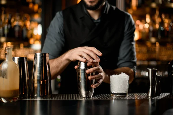 Чоловік бармен тримає в руках сталевий шейкер з коктейлем, готовим потиснути його — стокове фото