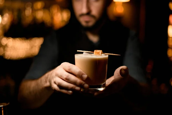 Cantinero masculino sirviendo la bebida alcohólica de color cremoso decorado con un caramelo en un pincho —  Fotos de Stock