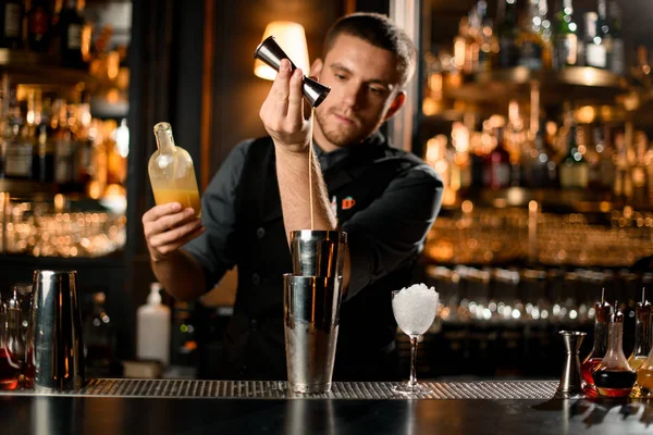 Samec barman nalévá liqour z jigger na profesionální ocelové třepačky — Stock fotografie