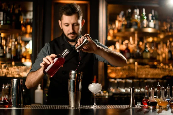 Erkek barmen kırmızı kahve likörünü jiggerdan profesyonel bir çeliğe döküyor. — Stok fotoğraf