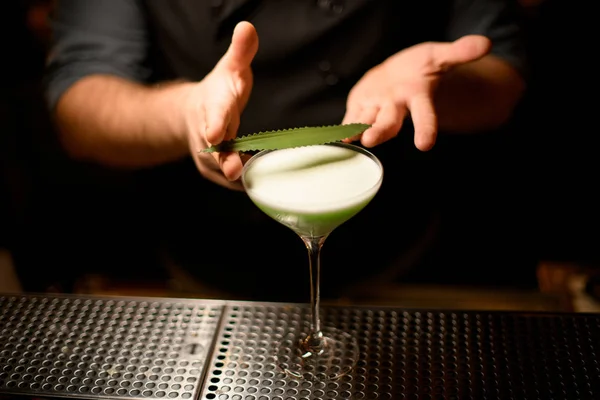 Barman a décoré la boisson cocktail alcoolisée de couleur verte crémeuse avec une feuille verte — Photo