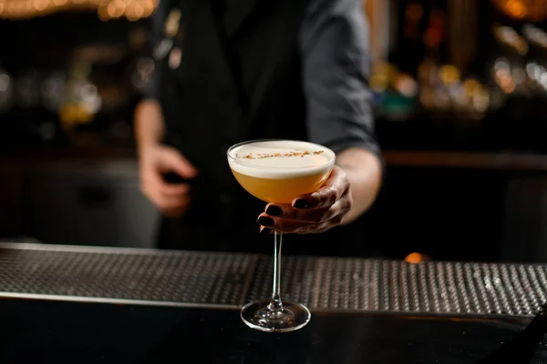Bartender flicka som serverar den gula alkoholhaltiga cocktail dryck med en vit avskum — Stockfoto