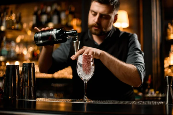 Cantinero macho vertiendo un alcohol de la botella trasera a un jigger —  Fotos de Stock