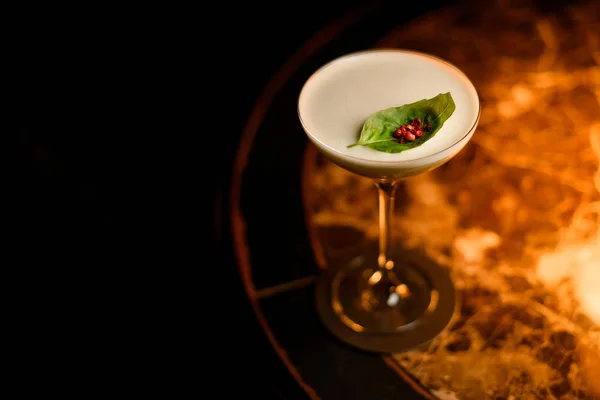 Gul krämig färg cocktail dekorerad med ett blad och röd paprika ärtor — Stockfoto