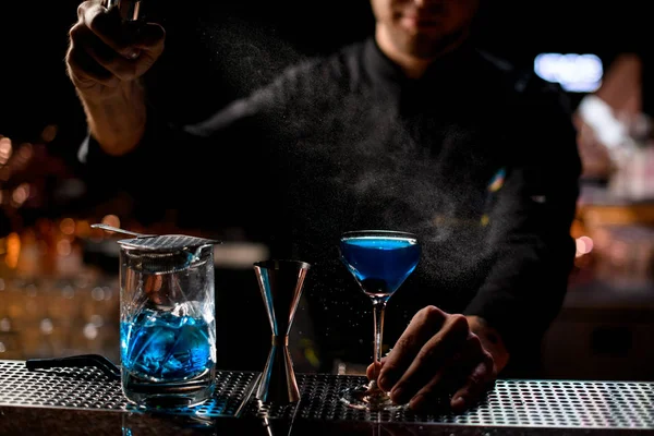 Cantinero profesional rociando sobre la bebida alcohólica azul con un amargo para servirla —  Fotos de Stock