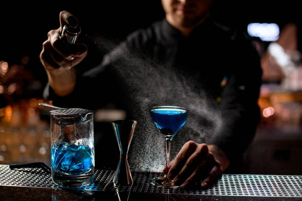 Professionele barman spuiten op de blauwe alcoholische drank met een bitter om het te serveren — Stockfoto