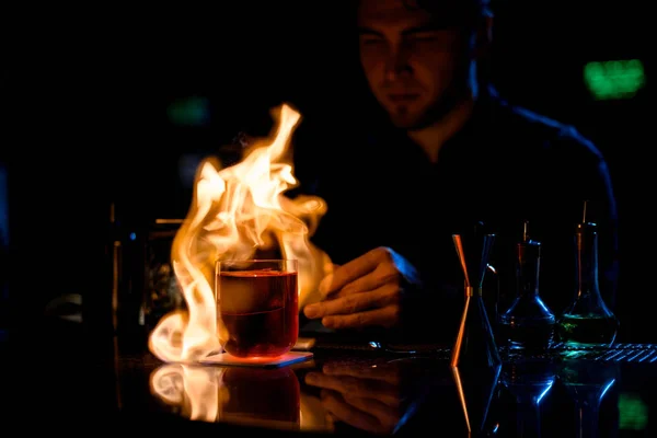 Profesionální barman podávající červený alkoholický koktejl s ledovým ohněm plátky citronu na pinzetě — Stock fotografie