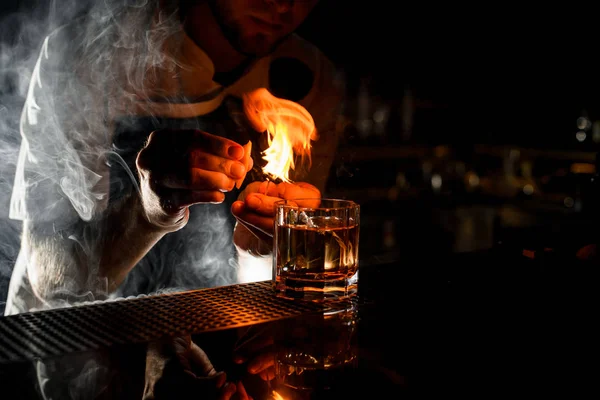 Мужчина-бармен, подающий прозрачный алкогольный коктейль со льдом, разбрызгивающий лимонный сок — стоковое фото