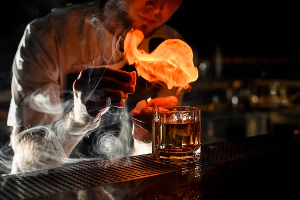 Barista professionista che serve il cocktail alcolico trasparente cospargendo con il succo di limone sul fiammifero facendo fuoco — Foto Stock