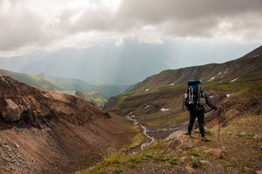 Equipped traveller posing on top of hill
