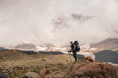 Traveller stands on top of the foggy mountain