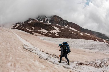Experienced hiker climbs up the foggy mountain