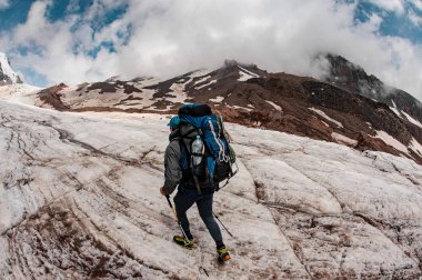 Experienced tourist climbs up the foggy mountain