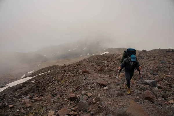 経験豊富な旅行者が霧深い山に登る — ストック写真