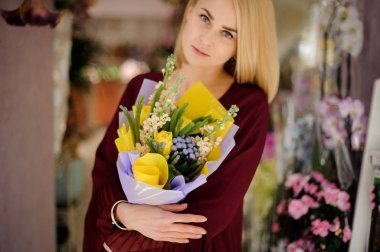 Sarı laleli buket tutan çekici bir kadın.