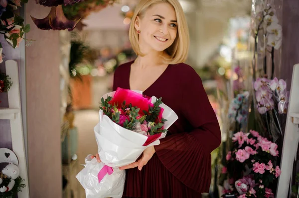 Smiling woman with bouquet in white paper