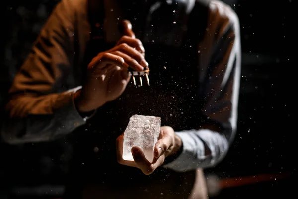 Bartender cutting ice with a special fork in bar in the dark — Stock Photo, Image