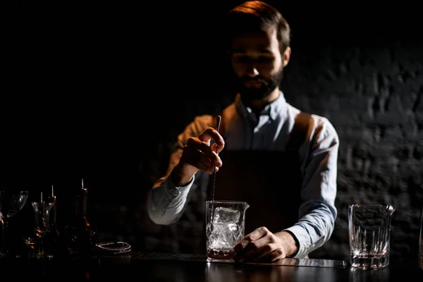 Cantinero macho agitando un cubo de hielo en el vaso con una cuchara especial para el vaso —  Fotos de Stock