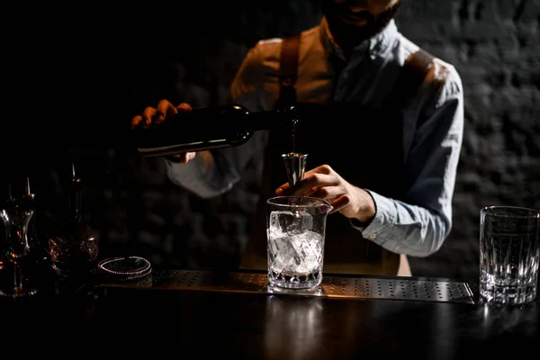 Cantinero masculino profesional sirviendo una bebida alcohólica de la botella a un jigger de acero —  Fotos de Stock