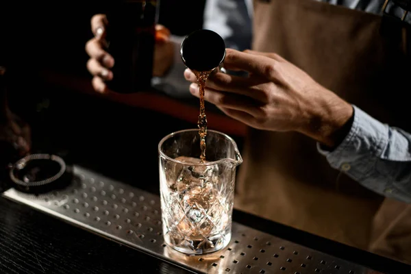 Επαγγελματίας μπάρμαν ρίχνει ένα καφέ αλκοολούχο ποτό από το jigger χάλυβα σε ένα γυάλινο κύπελλο — Φωτογραφία Αρχείου