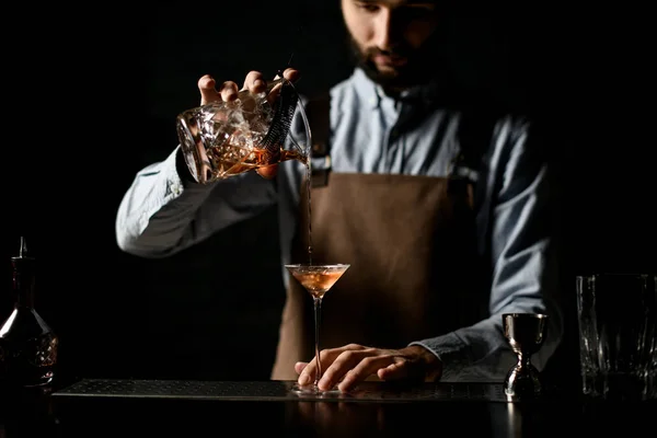 Professzionális csapos, aki alkoholos italt tölt a kis martinis pohárnak, tele ropogós jéggel. — Stock Fotó