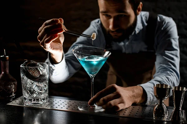 Professzionális csapos, aki egy kék alkoholos koktélt deacorál egy martinis pohárban egy tüskével. — Stock Fotó