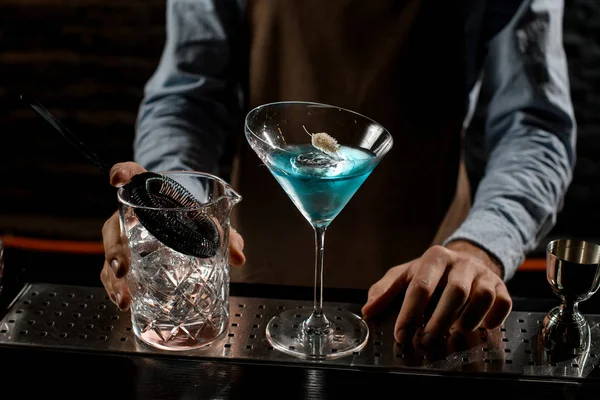 Profesjonalny barman serwujący niebieski koktajl alkoholowy w kieliszku martini ozdobionym suchym kolcem — Zdjęcie stockowe